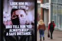 People make their way past a government coronavirus sign on Commercial road in Bournemouth, Dorset, during England's third national lockdown to curb the spread of coronavirus. Picture date: Tuesday February 16, 2021. PA Photo. See PA story HEALTH Coro
