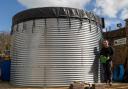 Mike Burks, managing director of The Gardens Group, in front of a 50,000-litre water tank, which was installed at Castle Gardens in Sherborne, Dorset in 2022 and connected to a Victorian plumbing system underneath the garden centre.
