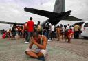 DEVASTATION: A survivor from Tacloban, which was devastated by Typhoon Haiyan gestures while sitting on the ground after disembarking an aircraft