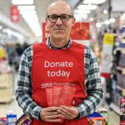 London, UK. 21 November, 2019. A Tesco volunteer holding a shopping list guide for donations at the launch of the Tesco Food Collection in the Surrey Quays Extra store.
