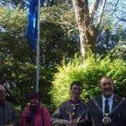 Luke Hughes, representing Weymouth Scouts, with the Mayor, rasies the UN flag.