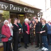 Mrs Hanney cuts the ribbon outside the shop with friends, family and public looking on.
