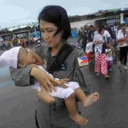 TRAGEDY: A Philippines Air Force crew member carries a baby who survived Typhoon Haiyan to an evacuation flight