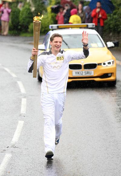Benjamin Hanger carries the Olympic Flame on the Torch Relay leg between Milborne St Andrew and Dorchester.