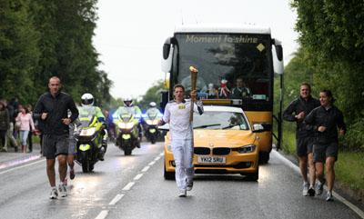 Benjamin Hanger carries the Olympic Flame on the Torch Relay leg between Milborne St Andrew and Dorchester. 
