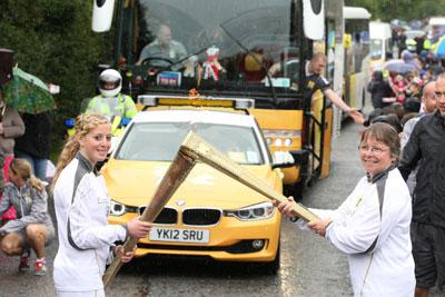 Anastasia Herring passes the Olympic Flame to Torchbearer  Marion Marchant on the Torch Relay leg between Milborne St Andrew and Dorchester.
