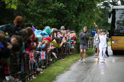 Nathan Blackie carries the Olympic Flame on the Torch Relay leg between Milborne St Andrew and Dorchester.