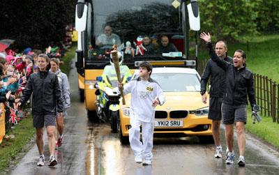 Torchbearer Nathan Blackie carries the Olympic Flame on the Torch Relay leg between Milborne St Andrew and Dorchester. 