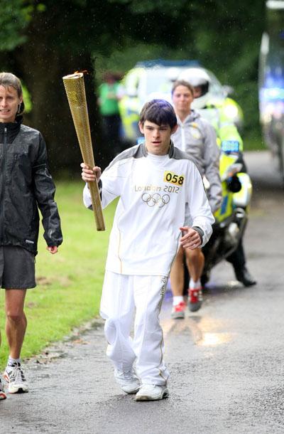 Torchbearer 058 Nathan Blackie carries the Olympic Flame on the Torch Relay leg between Milborne St Andrew and Dorchester. 