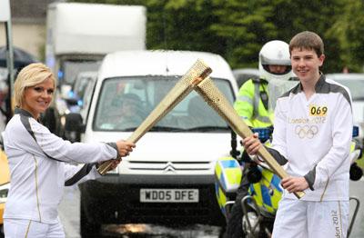 Thomas Hartley passes the Olympic Flame to Torchbearer 070 Natasha Jones on the Torch Relay leg between Dorchester and Winterbourne Abbas. 