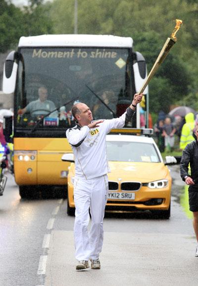 Andrew Rimmer carries the Olympic Flame on the Torch Relay leg between Dorchester and Winterbourne Abbas. 