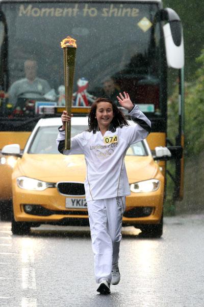 Katie Norman carries the Olympic Flame on the Torch Relay leg between Bridport and Lyme Regis. 