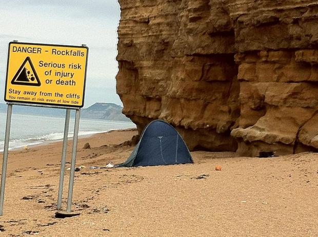 Campers pitch tent at foot of unstable cliff