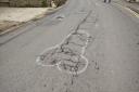 Crude graffiti drawn onto cracks and potholes on the B3162 in North Allington