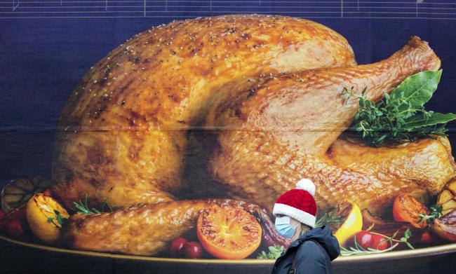 A shopper, wearing a Santa hat, passing a billboard poster featuring a Christmas turkey (PA)