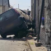 A car seen titled onto its side after crashing into a building