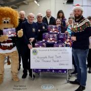 Weymouth Foodbank receiving check of £1,000 presented by Weymouth & Portland Lions Club President Ryan Hope, Kevin the Lion and several members of the Lions Club